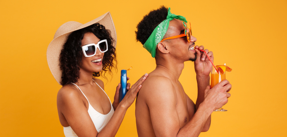 couple in beach clothing applies sunscreen