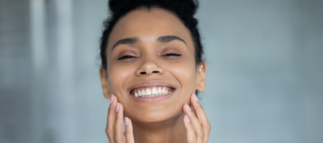 african woman with smooth skin smiles with closed eyes