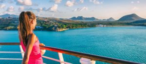a young woman looks over the rail of a cruise ship at the Caribbean coast