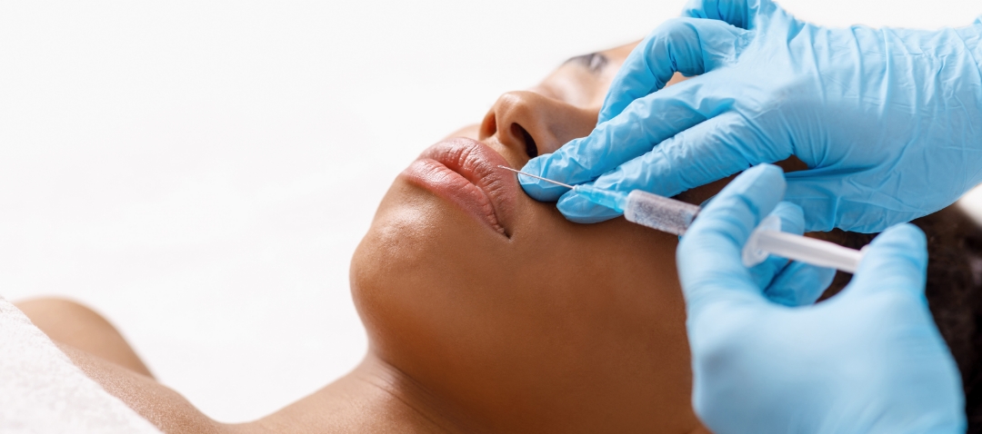 a black woman receives a botox injection in her upper lip