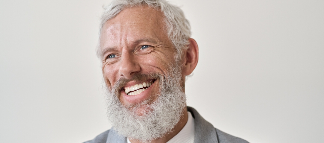 a middle aged white man with a grey beard smiles deeply