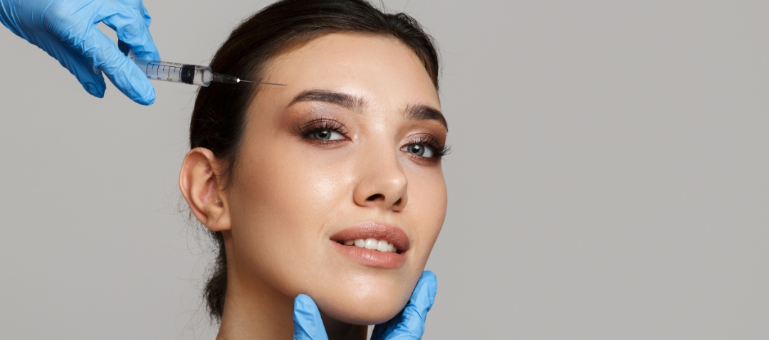 a woman grins slightly while receiving a forehead injection