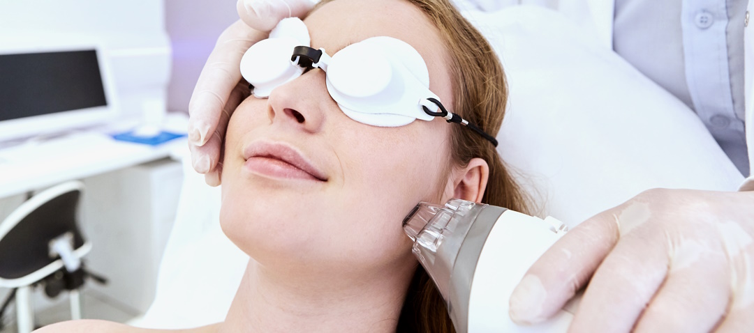 Young woman gets laser therapy on her face with the Fraxel laser for skin rejuvenation