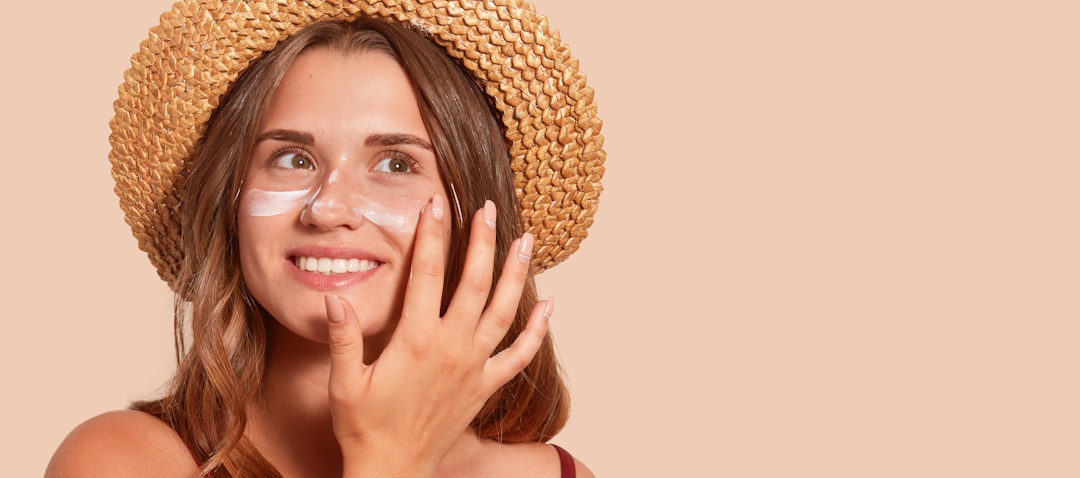 woman in straw hat with sunscreen on her cheeks